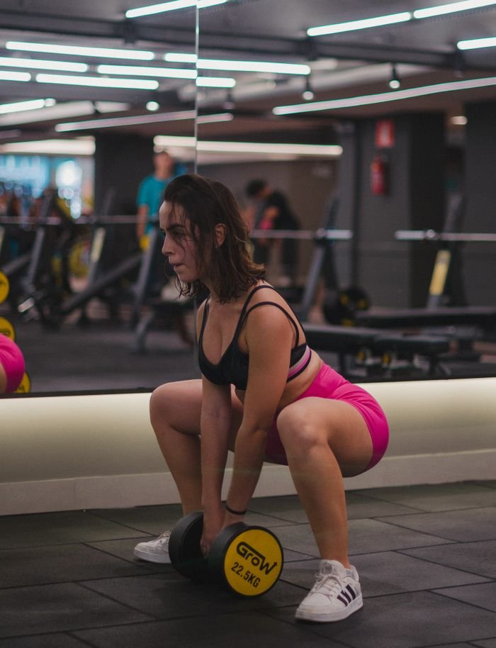 our-story Athletic woman focuses on weightlifting in a modern, well-equipped gym.