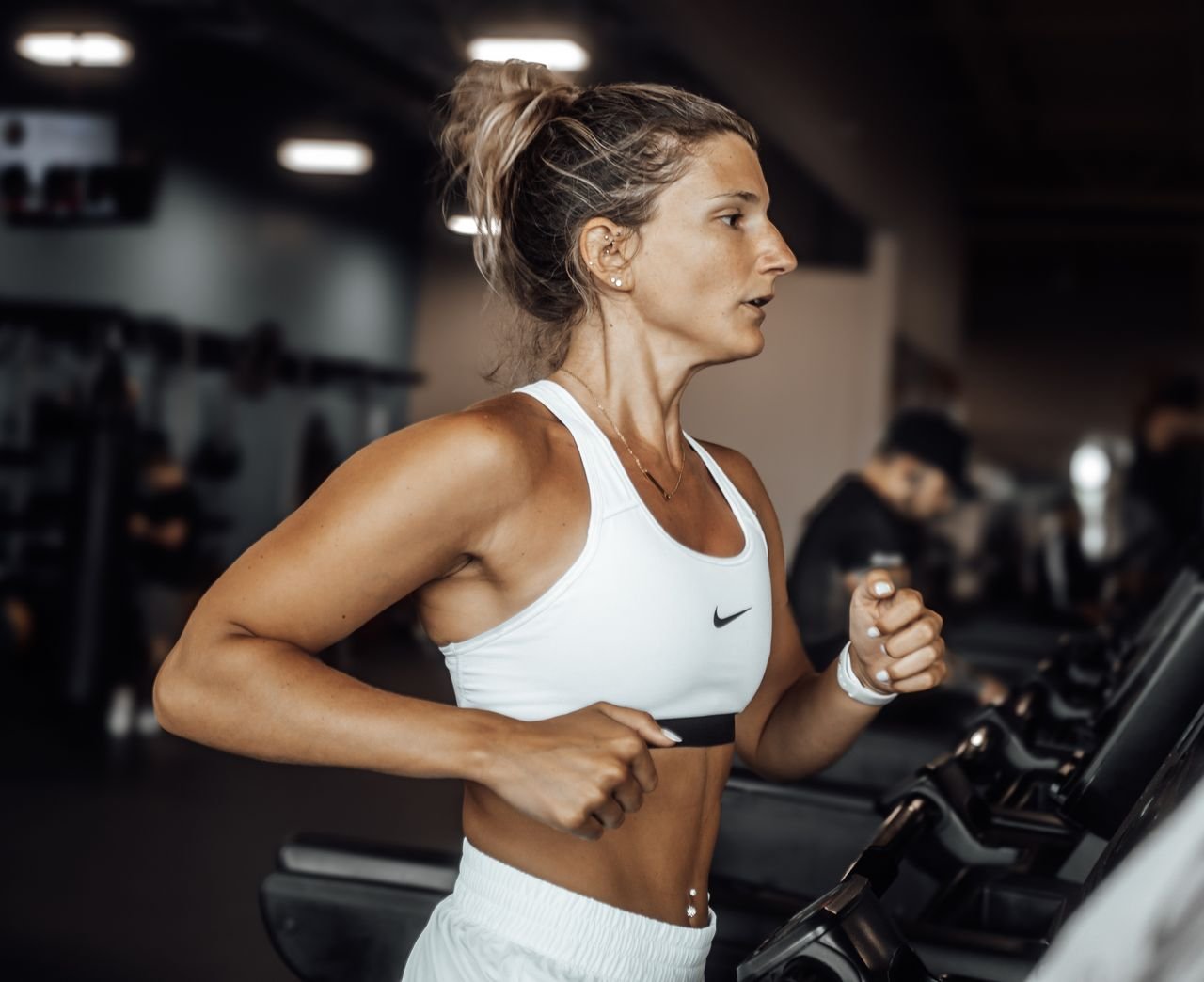 services-03 Fit woman exercising on a treadmill in a modern gym setting.